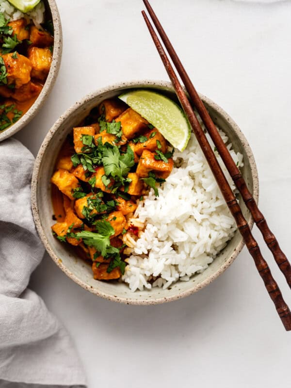 a bowl of coconut curry tofu with chopsticks on top and a napkin on the side