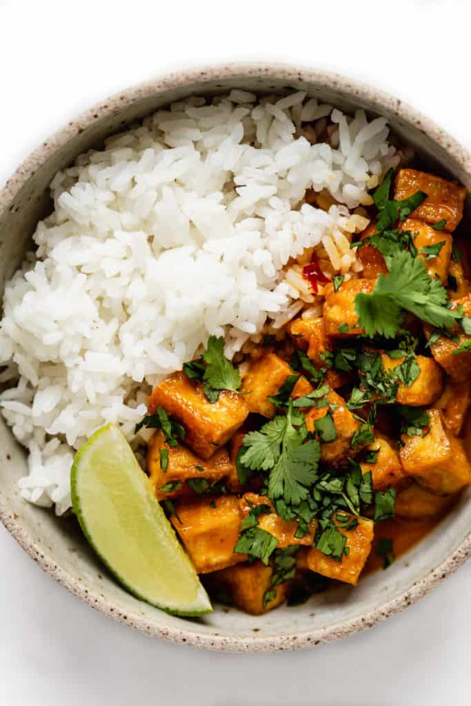 coconut curry tofu topped with cilantro in a bowl with rice on the side