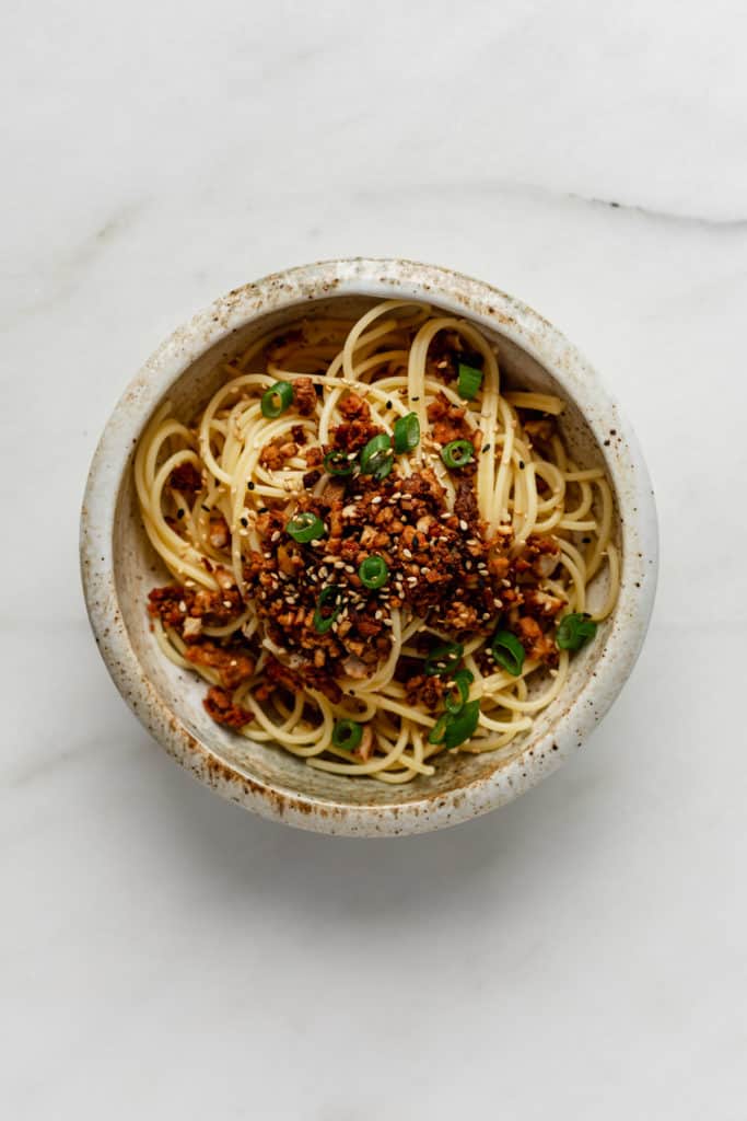 A bowl of noodles topped with vegan ground meat and green onions