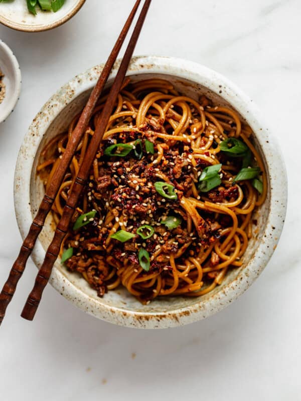 Vegan dan dan noodles topped with green onions and sesame seeds