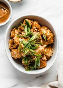 A bowl of Thai cauliflower wings topped with green onions and sesame seeds