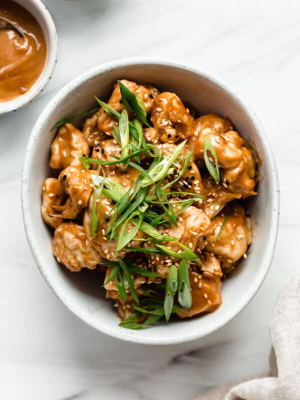 A bowl of Thai cauliflower wings topped with green onions and sesame seeds