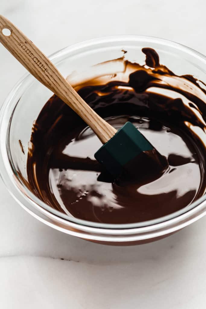 a mixing bowl of melted chocolate with a spatula in it