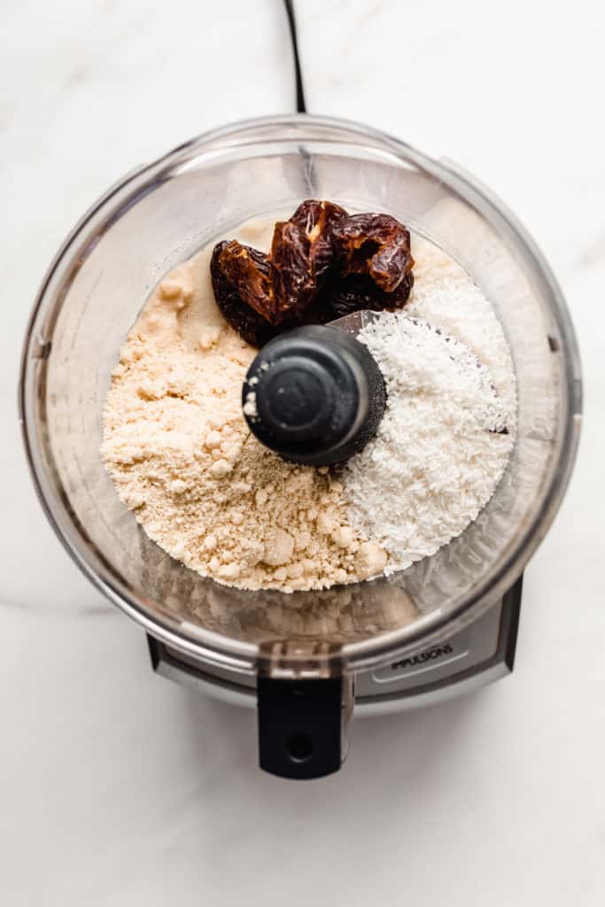 a food processor with shredded coconut, almond flour and dates
