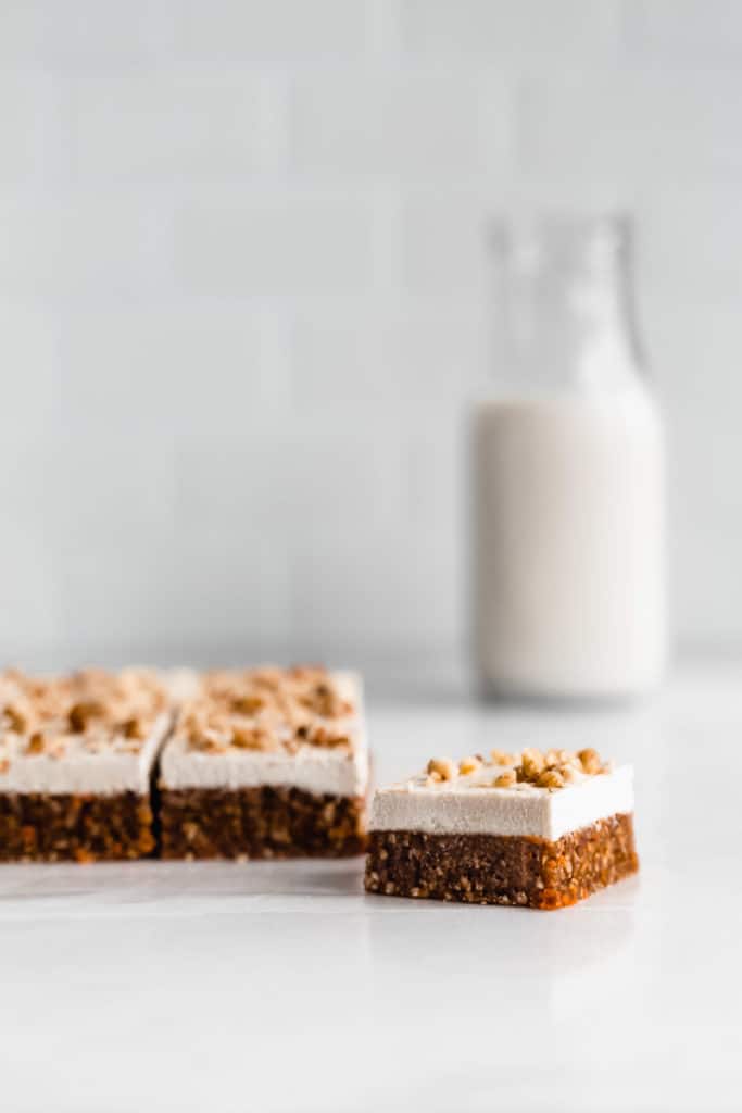 raw carrot cake bars on a marble counter with a bottle of milk in the background