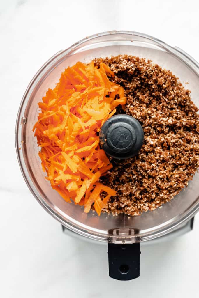 shredded carrots and raw carrot cake dough in a food processor