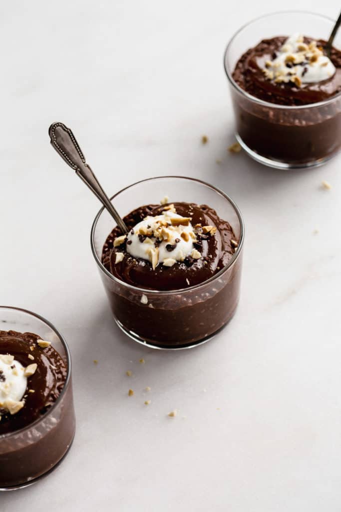 a cup of snickers chia pudding topped with cacao nibs, crushed peanuts and yogurt