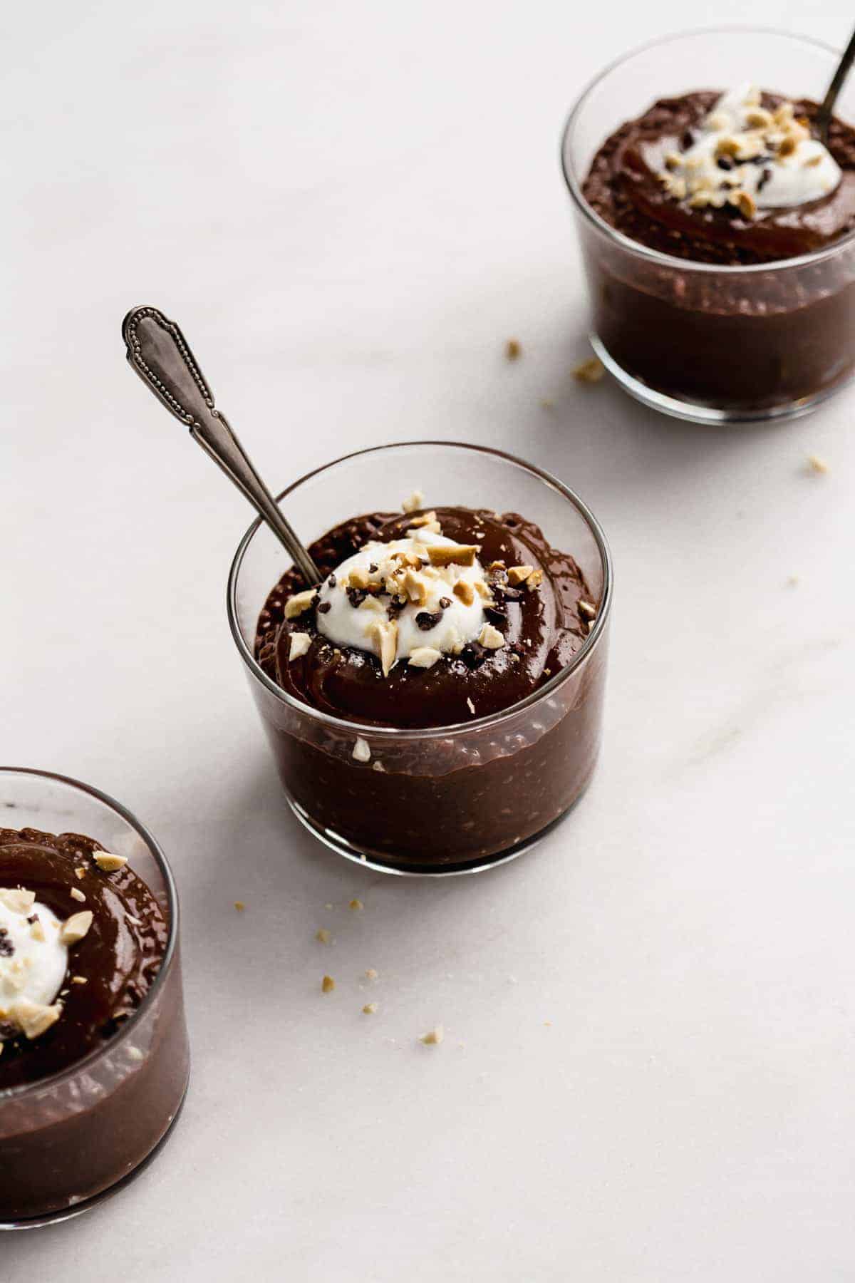 a cup of snickers chia pudding topped with cacao nibs, crushed peanuts and yogurt