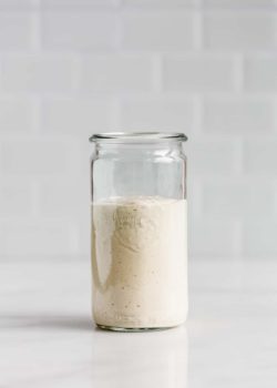A jar of vegan caesar salad dressing on a white counter