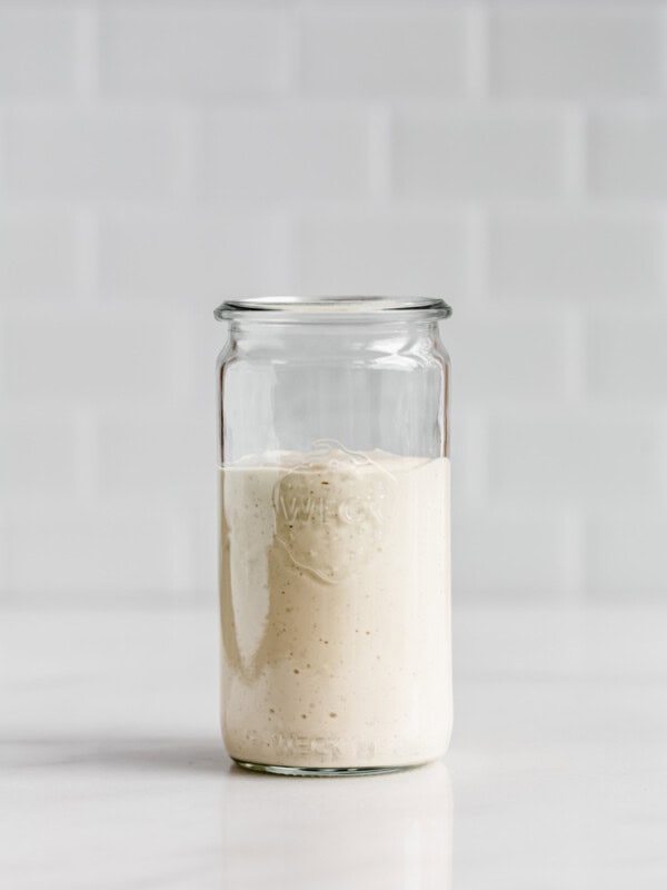 A jar of vegan caesar salad dressing on a white counter