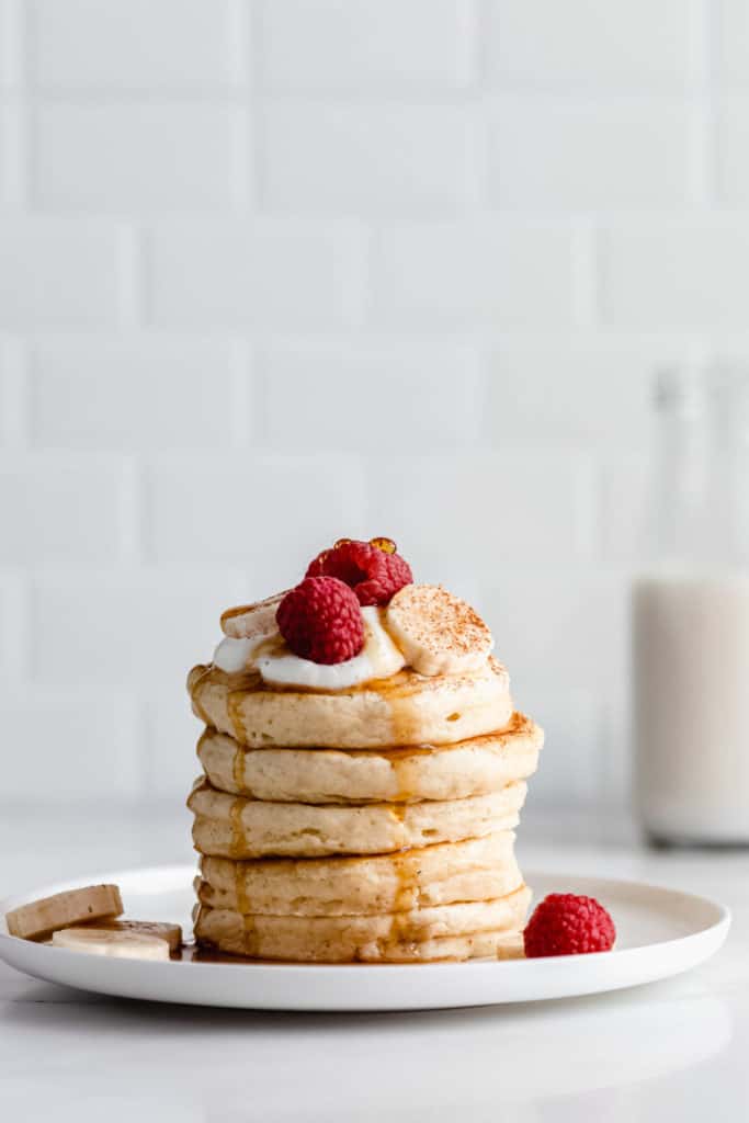 a stack of vegan oatmeal pancakes topped with raspberries and bananas