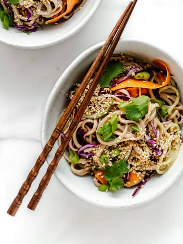 A bowl of soba noodle salad with vegetables topped with cilantro