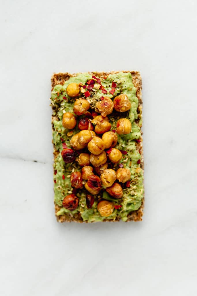 a Ryvita cracker topped with avocado and crispy chickpeas