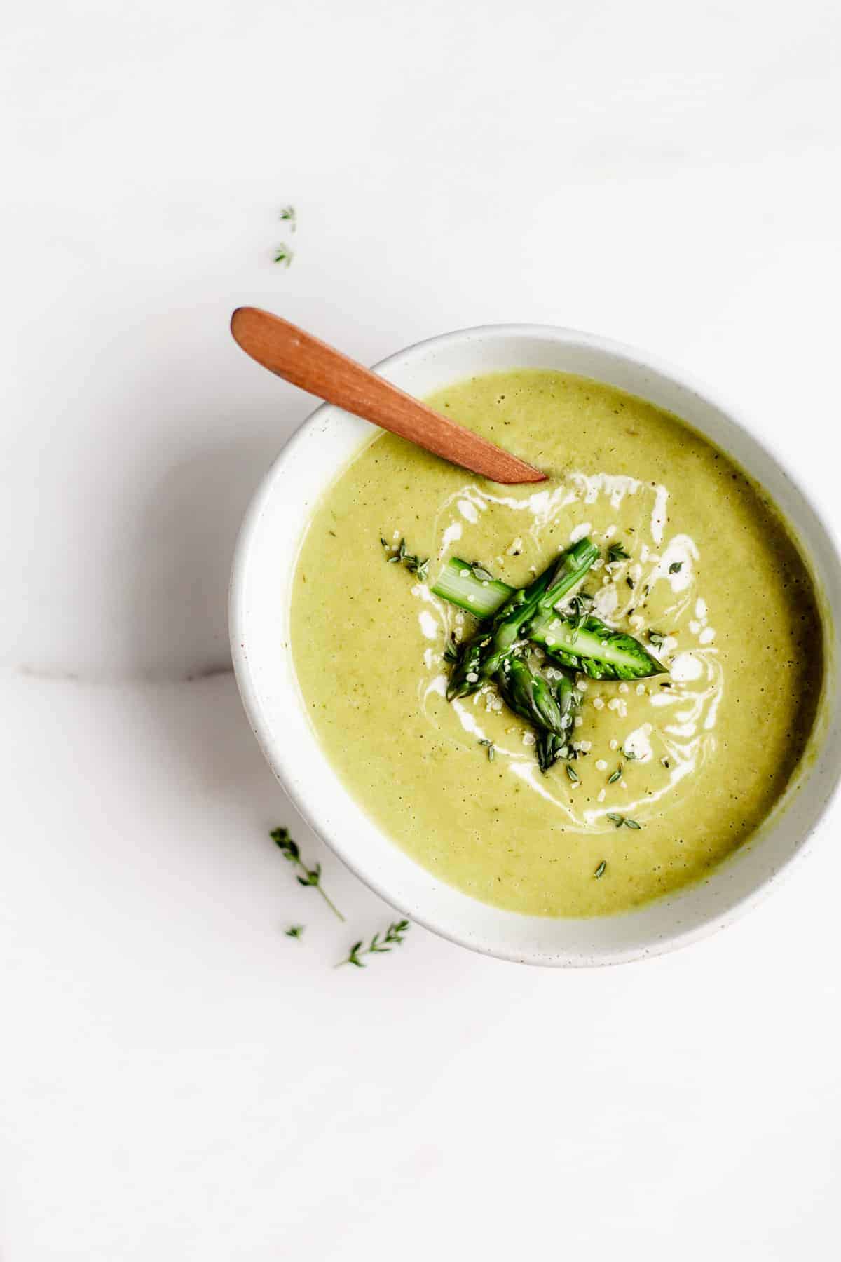 asparagus soup in a white bowl with chopped asparagus on top