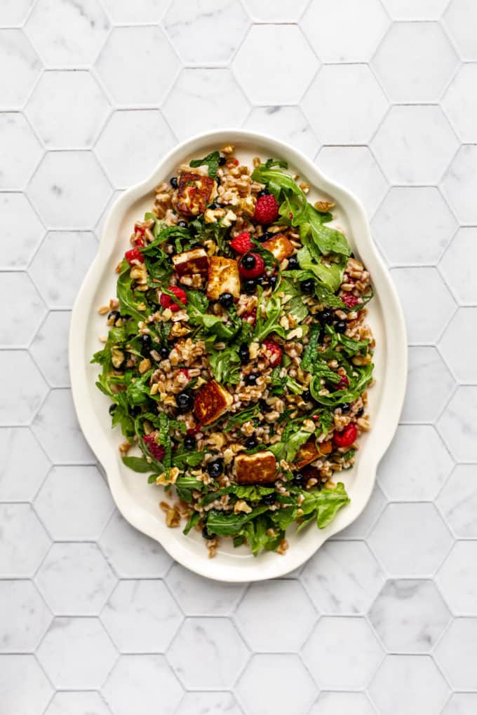 A white serving platter with farro and halloumi salad on it