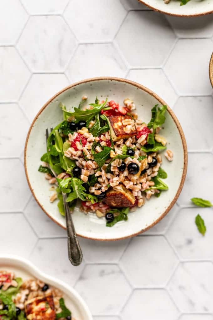 A round white plate with farro and halloumi salad in it