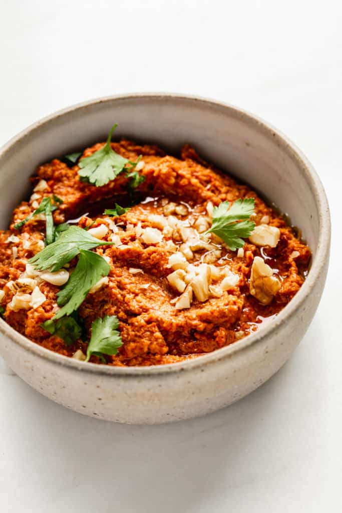 roasted red pepper dip in a ceramic bowl with parsley on top