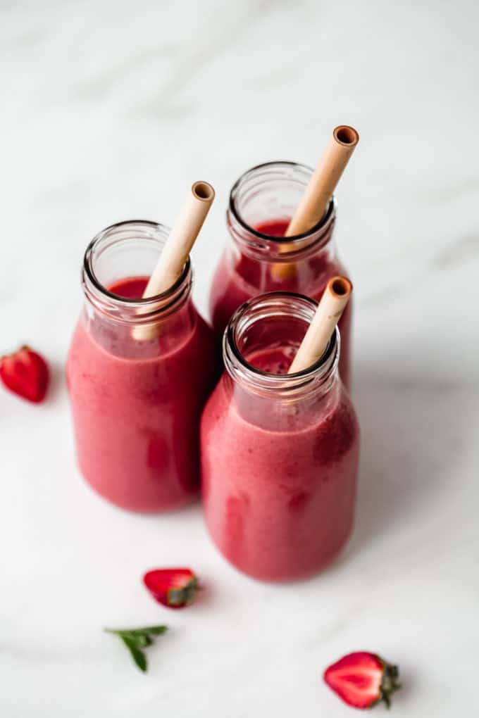 three jars of red berry smoothies on a marble counter