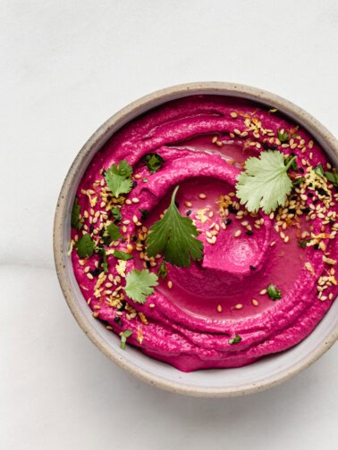 Roasted Beet Hummus in a bowl topped with cilantro and sesame seeds