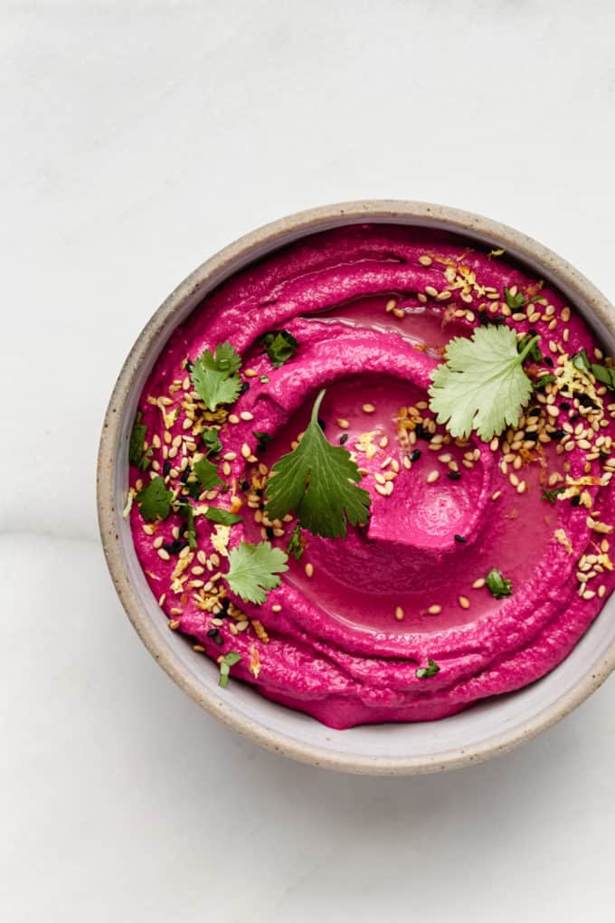 Roasted Beet Hummus in a bowl topped with cilantro and sesame seeds