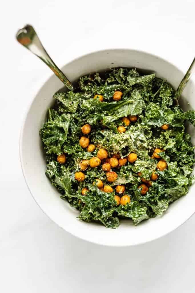freshly chopped kale covered with smokey roasted chickpeas in a white bowl on a white marble countertop, summer salads with kale