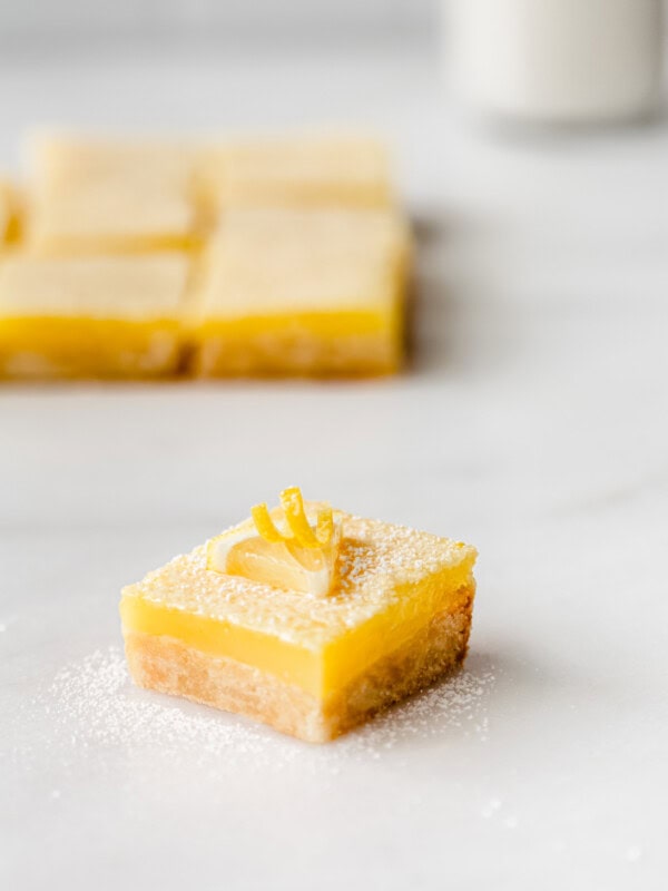 a lemon square topped with a slice of lemon on a marble board