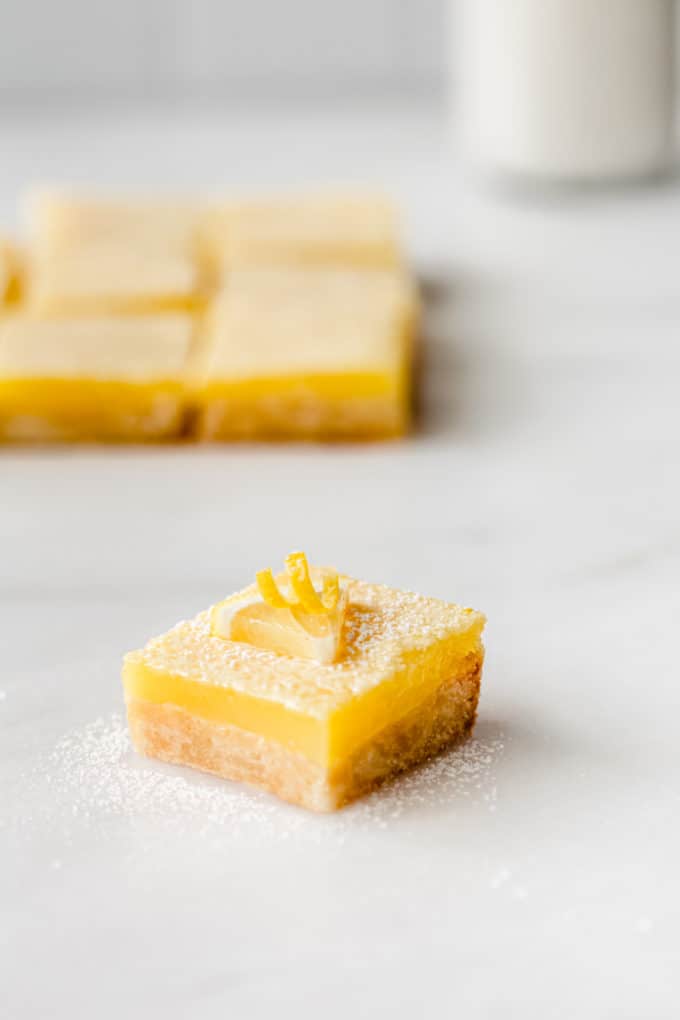 a lemon square topped with a slice of lemon on a marble board