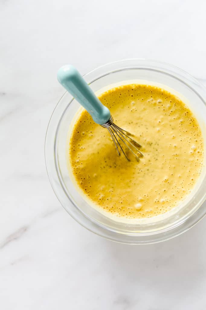 A clear mixing bowl with blended mangos, cashew milk and chia seeds in it