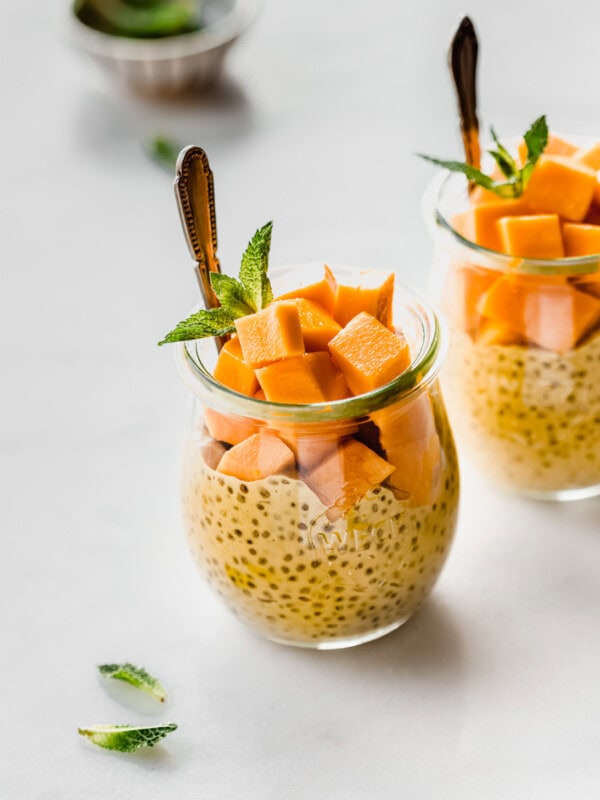 a jar filled with mango chia pudding, cubed mangos and fresh mint
