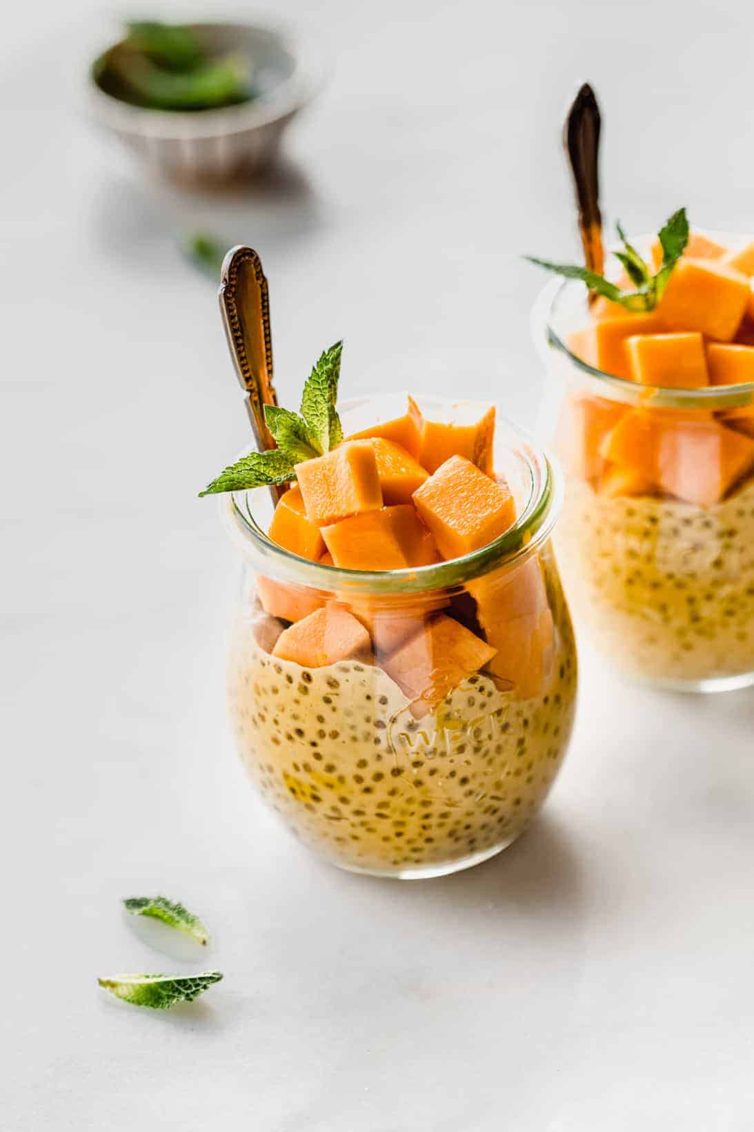 a jar filled with mango chia pudding, cubed mangos and fresh mint