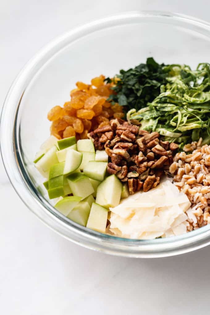 farro, apples and vegetables in a clear mixing bowl