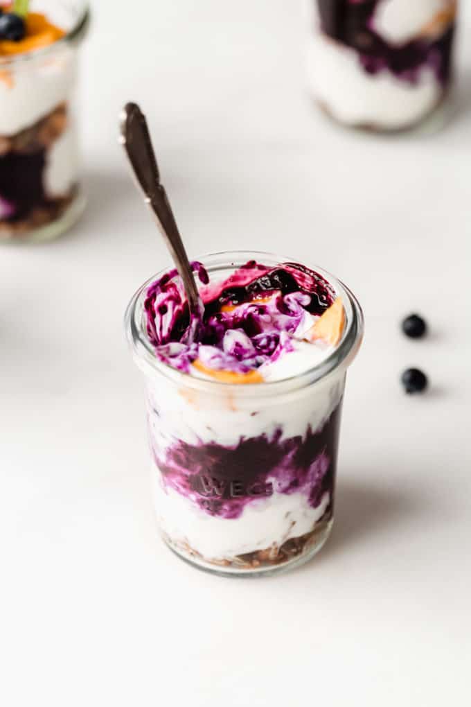 a jar of yogurt with blueberry compote and mango