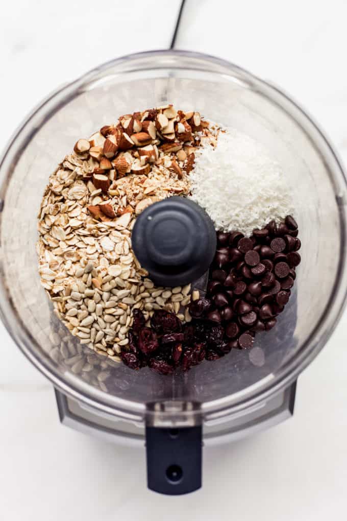 a food processor with nuts, seeds, shredded coconut and chocolate chips in it