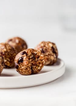 an energy ball on a white plate with a bite taken out of it