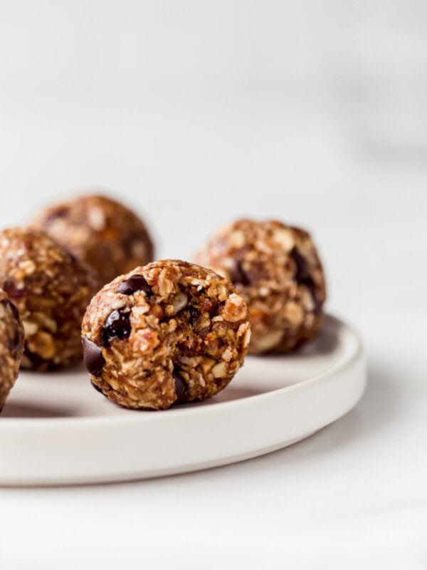 an energy ball on a white plate with a bite taken out of it