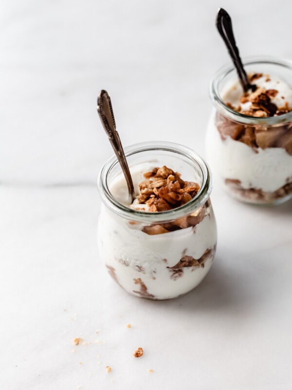 two jars of apple pie parfaits with spoons in them