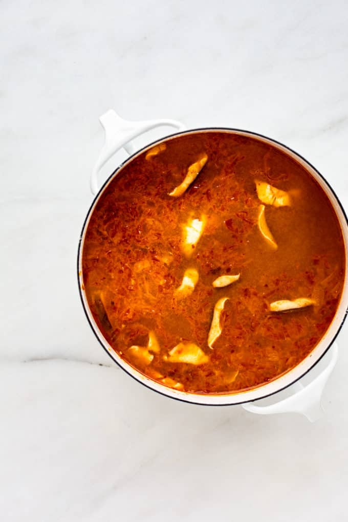 a white pot with kimchi ramen in it