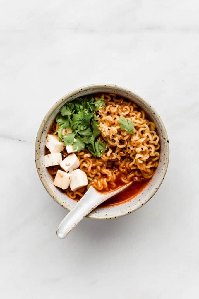 a bowl of kimchi ramen with tofu and cilantro