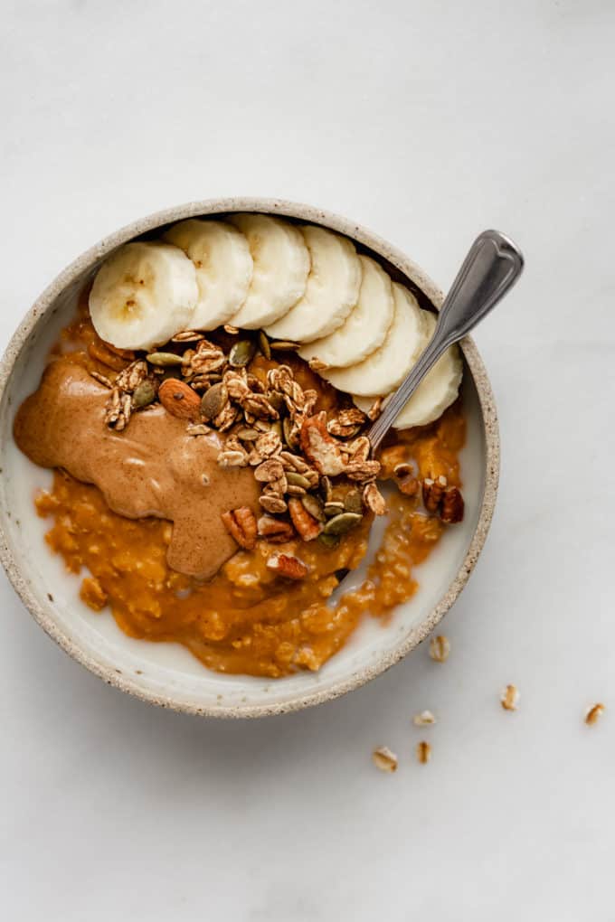pumpkin oatmeal in a bowl topped with bananas and granola