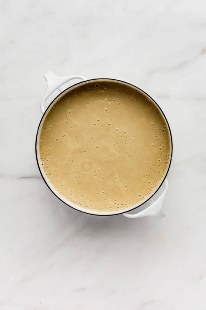 a pot of roasted garlic soup on a marble board