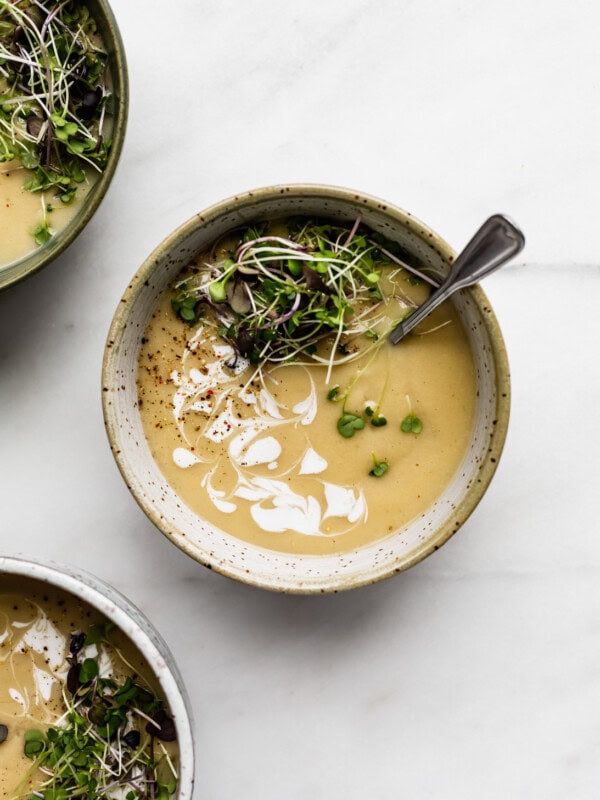 a bowl of roasted garlic soup topped with radish sprouts