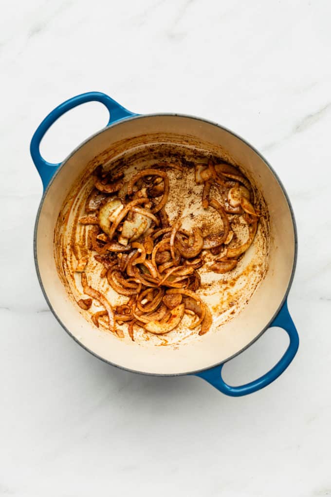 onions and spices in a blue pot