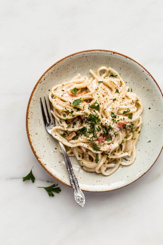 A plate of vegan carbonara topped with parsley