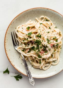 Vegan carbonara on a white ceramic plate with a fork on the side