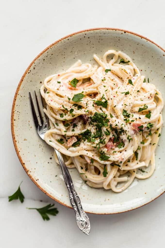 Vegan carbonara on a white ceramic plate with a fork on the side