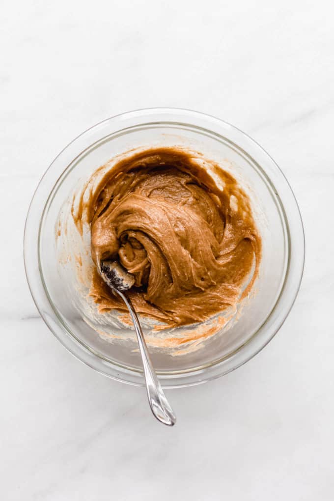 almond butter in a clear mixing bowl with a spoon