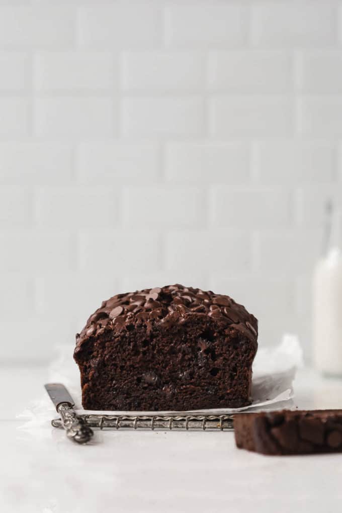 A loaf of chocolate pumpkin bread on a marble table with a slice cut out of it