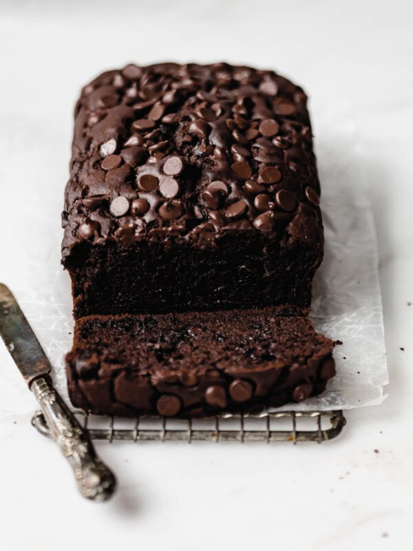 A loaf of healthy chocolate pumpkin bread topped with chocolate chips with a small knife on the side
