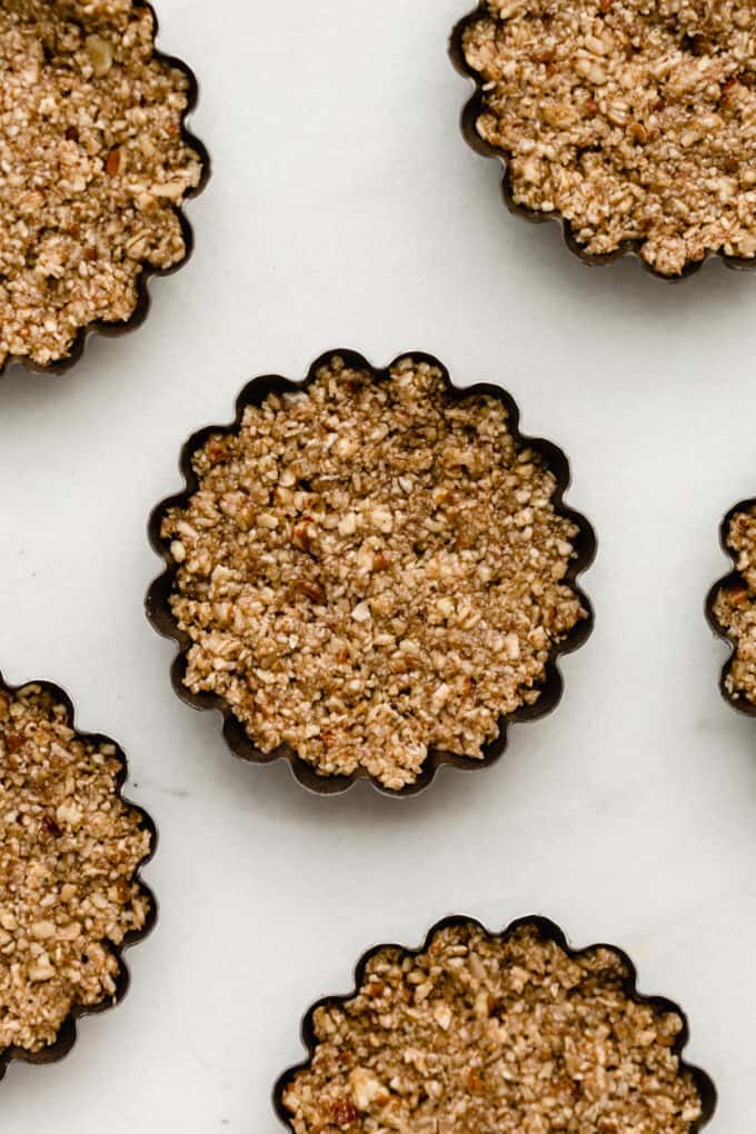 mini tart pans with pecan crust in them