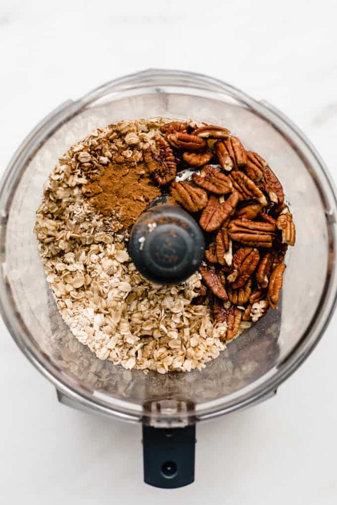 A food processor with oats, pecans and cinnamon in it